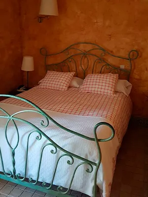 Hostería Natura: habitación doble con cama de forja verde y paredes ocre