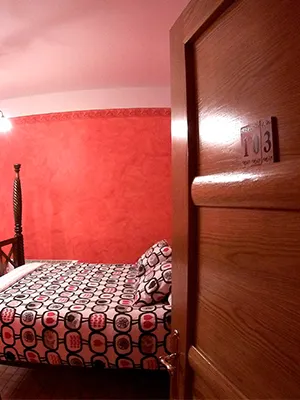 Hostería Natura: habitación con paredes rojas y colcha estampada